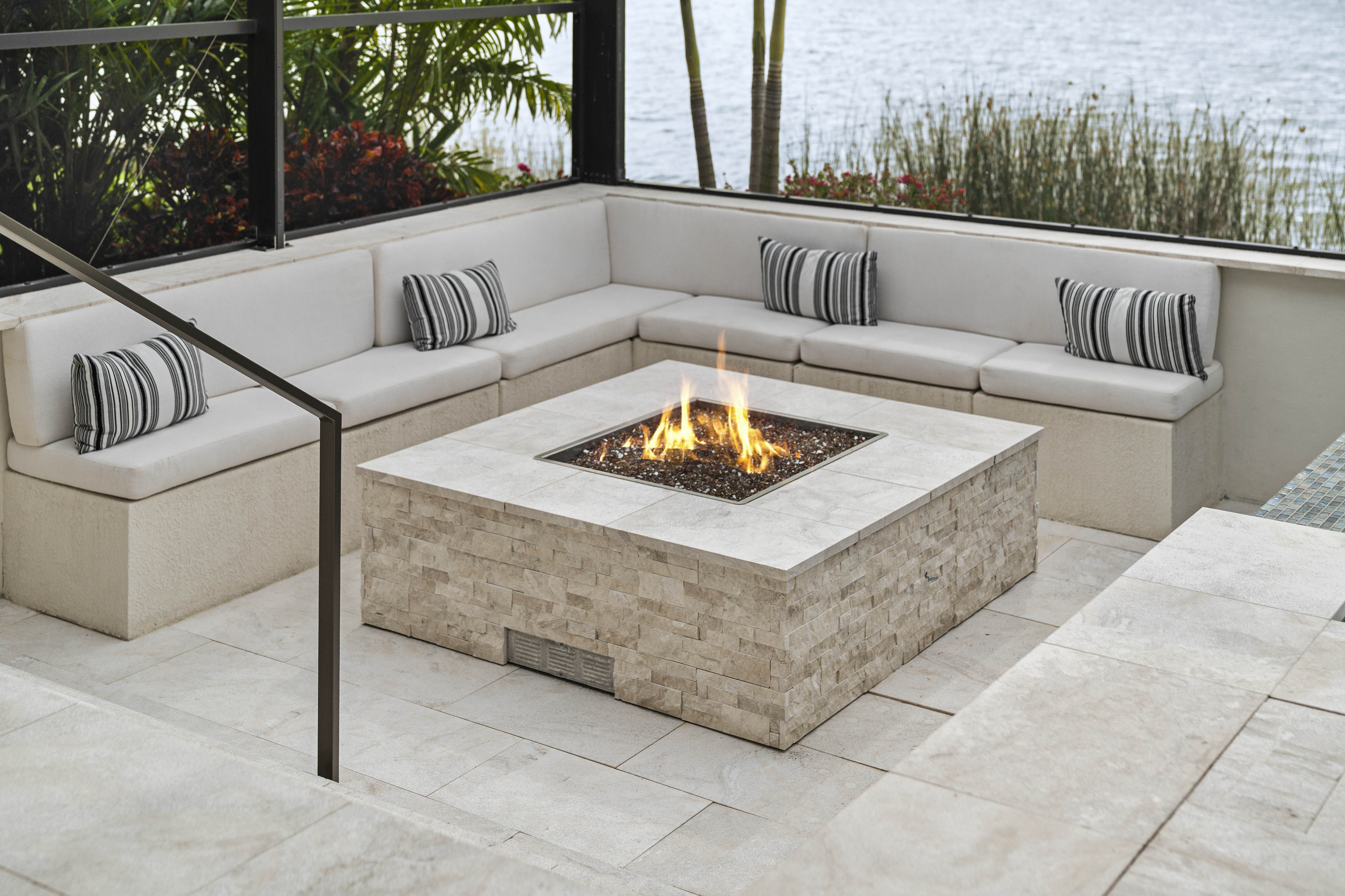 Fire bowl feature at night adjacent to pool, amber flame against dark water