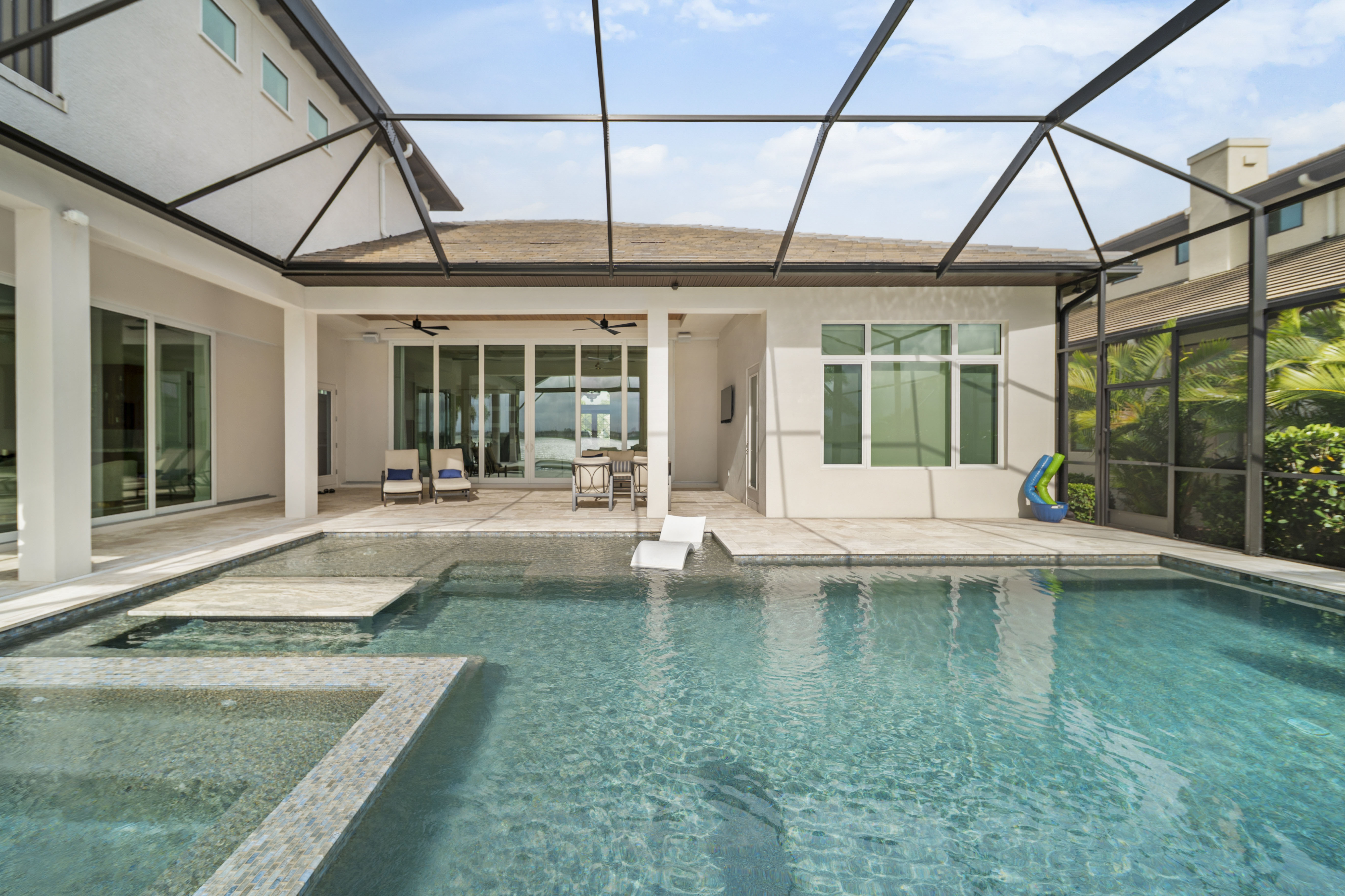 Free-form pool with natural stone coping and lush tropical landscaping at golden hour - Swim Inc. custom pool Sarasota