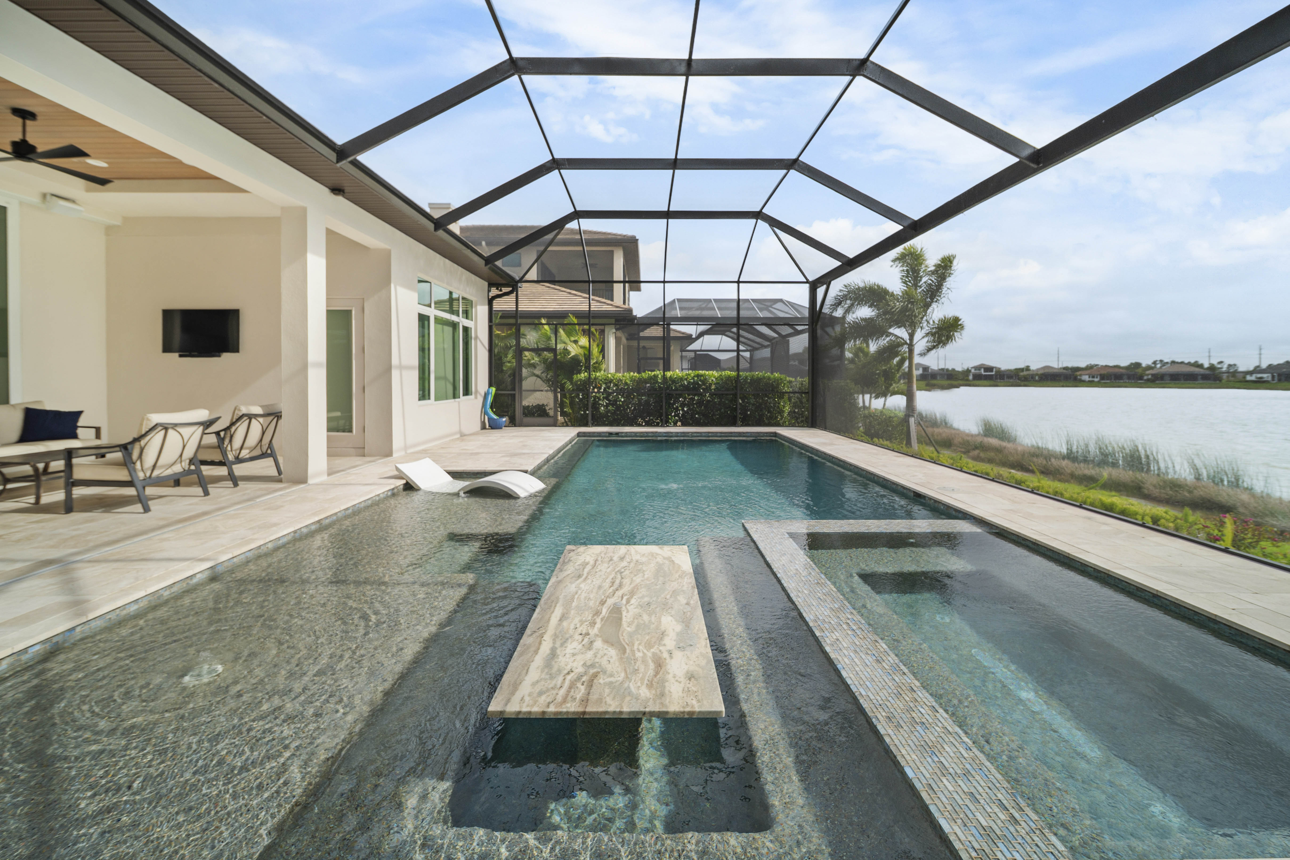 Close-up detail of premium pool renovation finish work showing pebble plaster texture, glass mosaic tile coping, and warm LED accent lighting, Swim Inc. craftsmanship